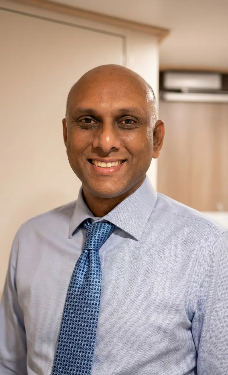 Anup Rai, smiling in a blue shirt and tie